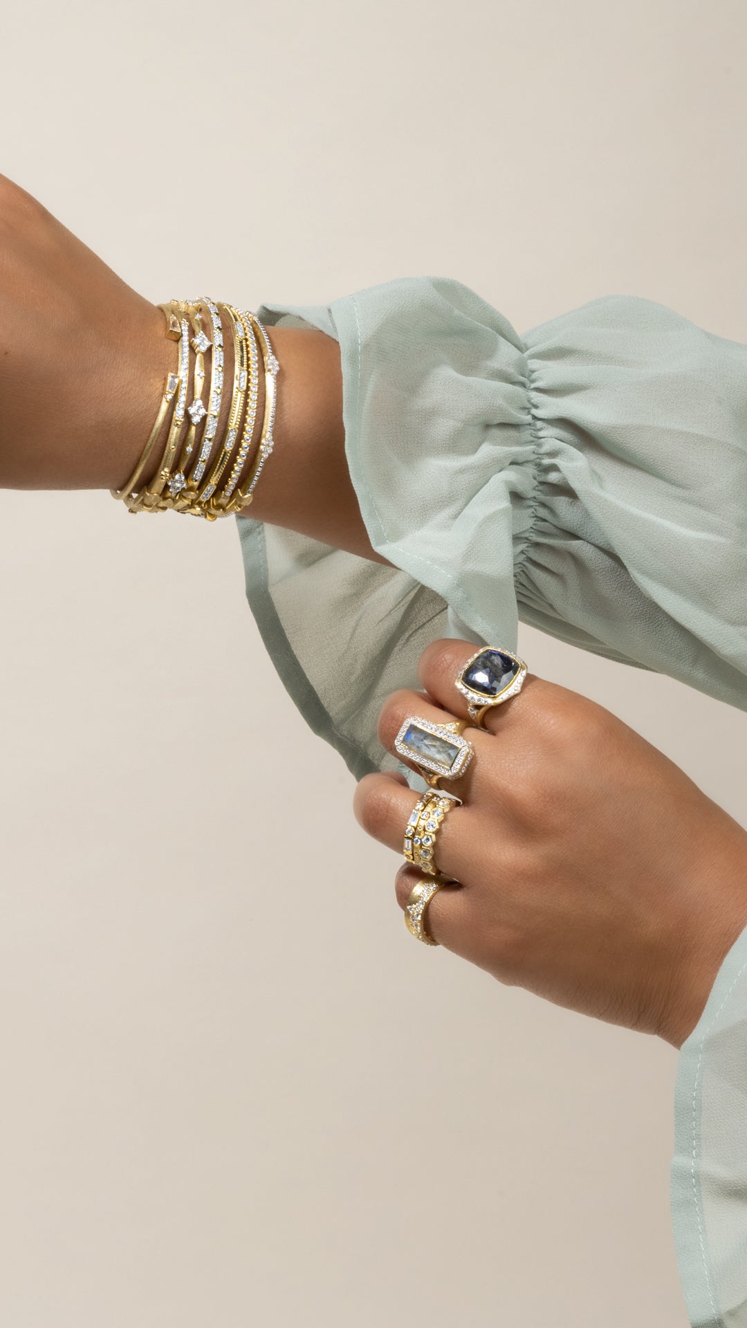 A woman's hands wearing stacks of bracelets and many different styles of rings