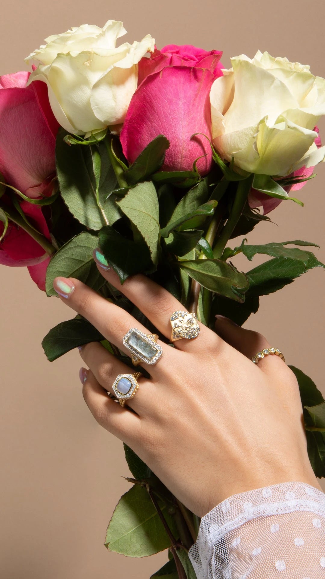 A woman's hand holding roses, adorned with beautiful rings on her fingers