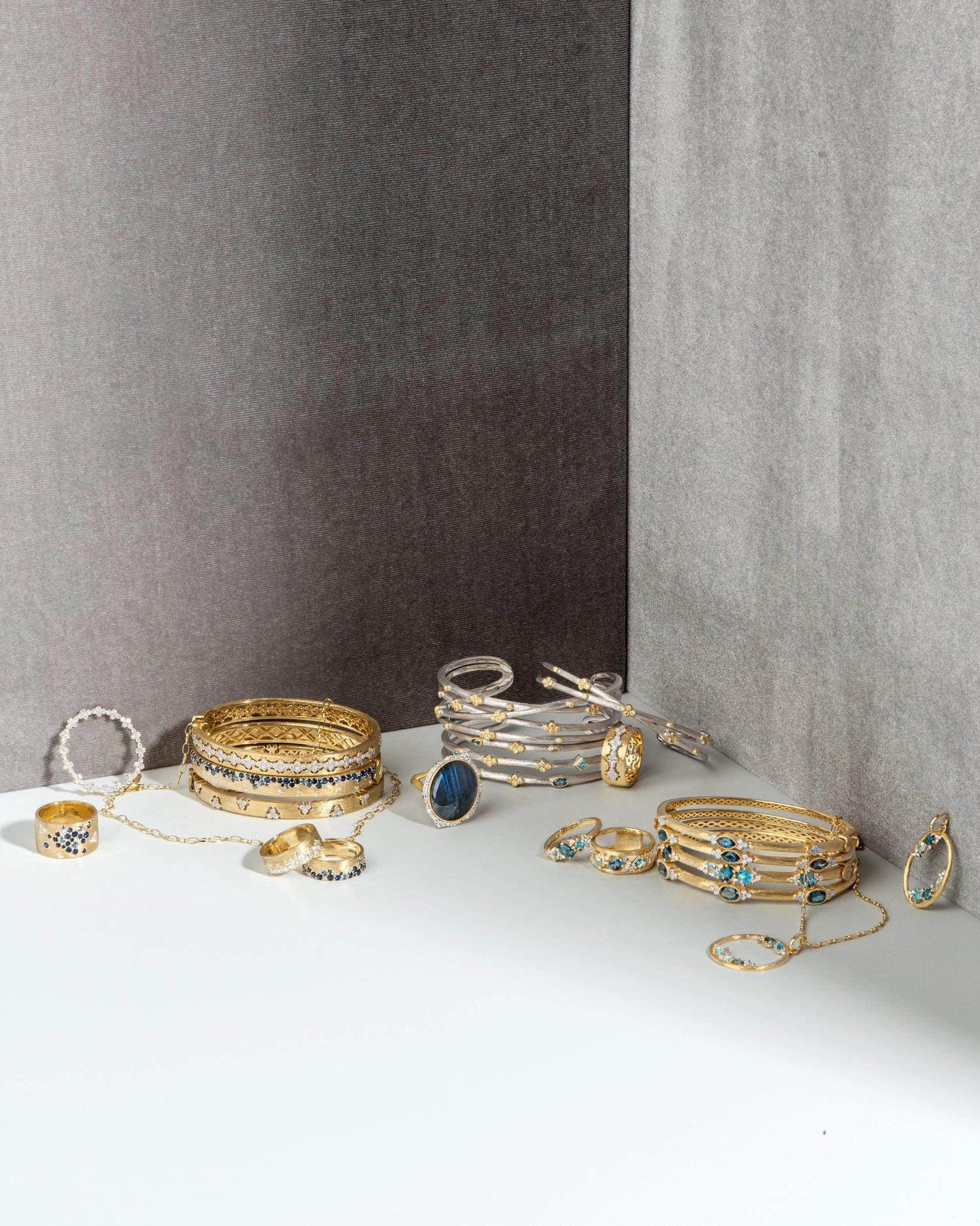 Stacks of gold and silver bracelets with rings and necklaces interspersed